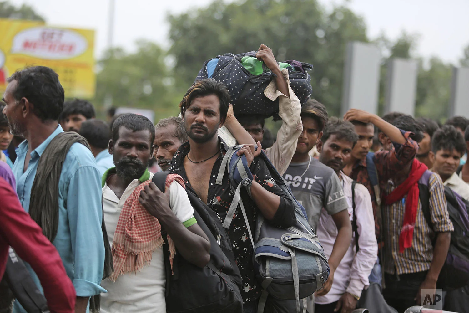 Indian migrant laborers carry their luggage and prepare to leave the region, at a railway station in Jammu, India, Wednesday, Aug. 7, 2019. (AP Photo/Channi Anand)