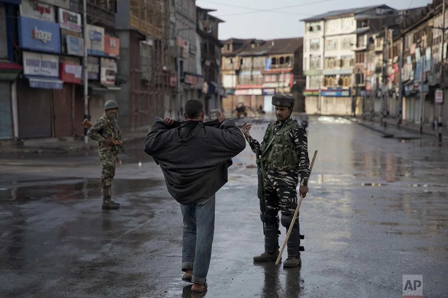 An Indian paramilitary soldier orders a Kashmiri to lift his robe before frisking him during curfew in Srinagar, Indian controlled Kashmir, Thursday, Aug. 8, 2019. (AP Photo/Dar Yasin)