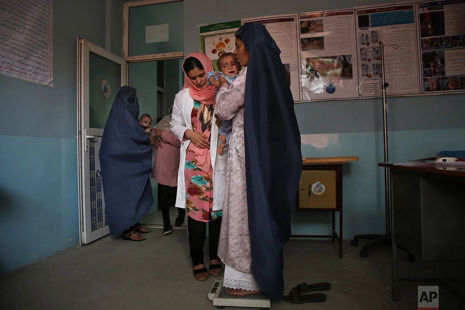 A doctor checks the weight of a mother and her son at a UNICEF clinic for children suffering from malnutrition in Jabal Saraj, north of Kabul, Afghanistan, Aug. 26, 2019. (AP Photo/Rafiq Maqbool)