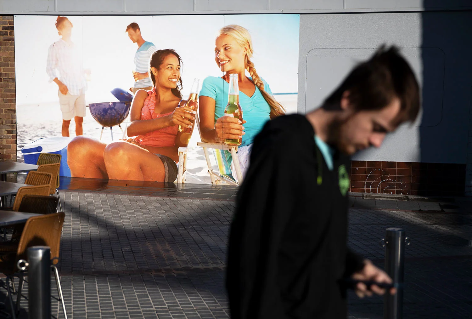Sam Ware, 22, walks past a billboard while out on a morning walk from the hostel where he is staying at The Entrance, Central Coast, Australia, Thursday, July 25, 2019. (AP Photo/David Goldman)