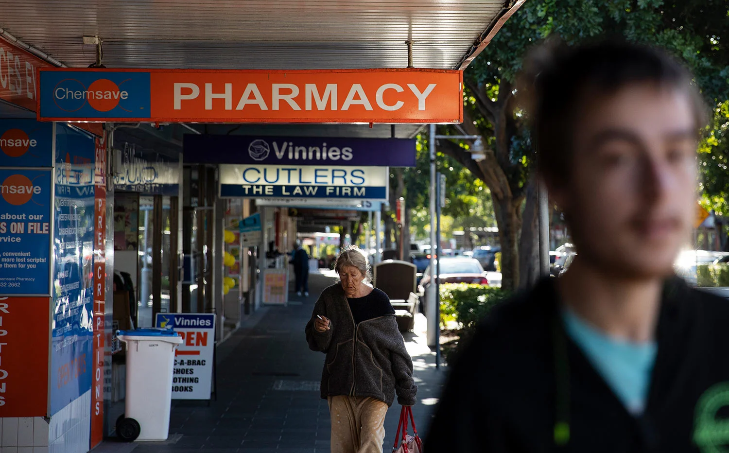 Sam Ware, 22, right, walks by the pharmacy where he used to get some of his opioid prescriptions filled in The Entrance, Central Coast, Australia, Thursday, July 25, 2019.(AP Photo/David Goldman)