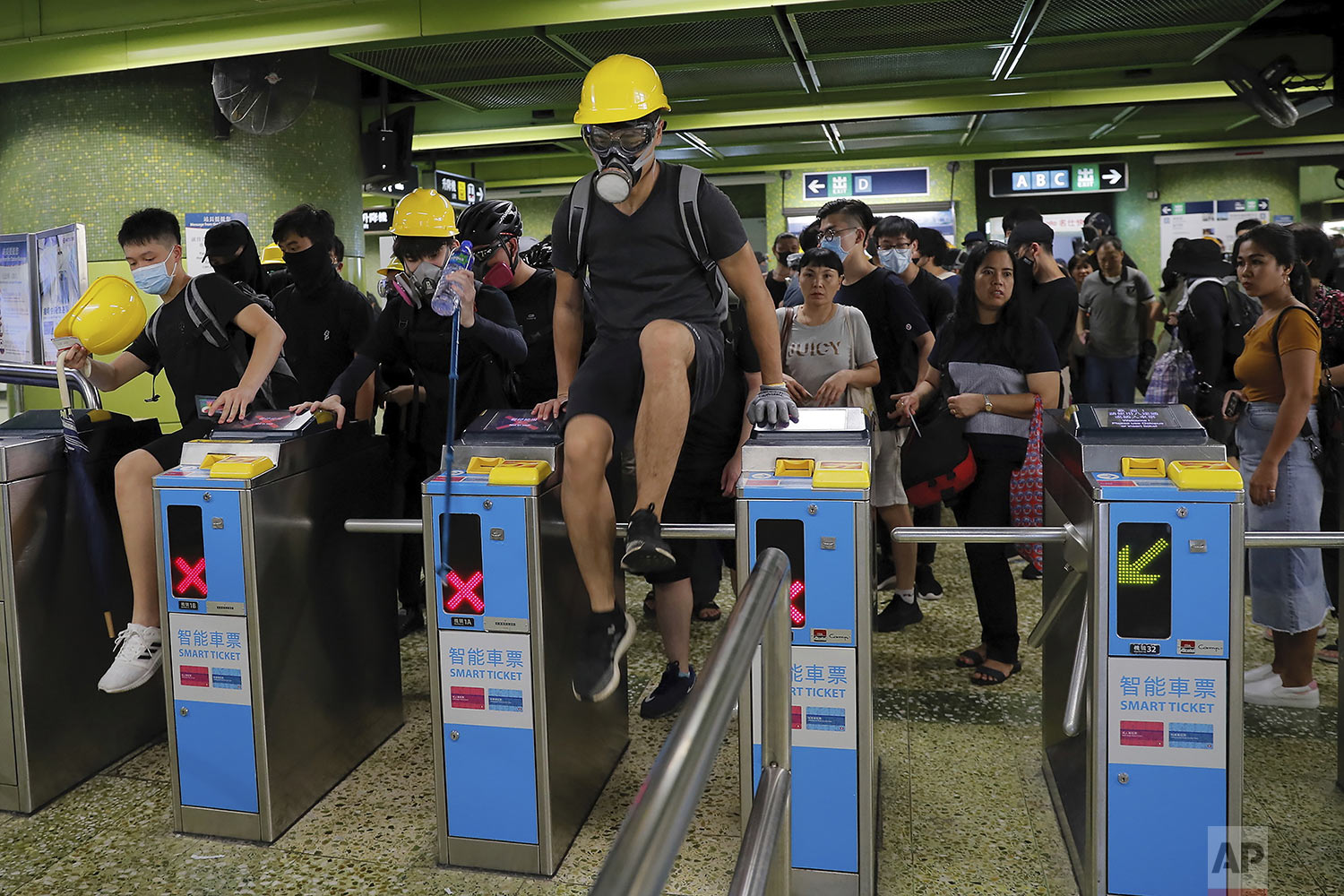  Protesters jump over MTR gates as they move to another destination during the anti-extradition bill protest in Hong Kong, Sunday, Aug. 11, 2019.  (AP Photo/Kin Cheung) 