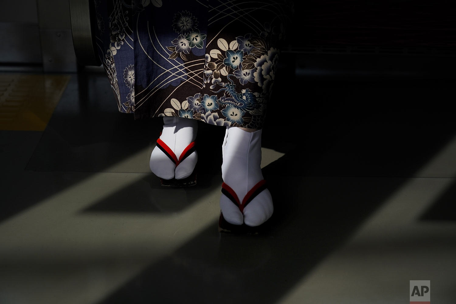  A woman wearing a kimono and traditional Japanese sandals called "geta"" is lit by the afternoon sunlight coming through the window of a train, in Kawagoe, near Tokyo, Friday, Aug. 16, 2019. (AP Photo/Jae C. Hong) 