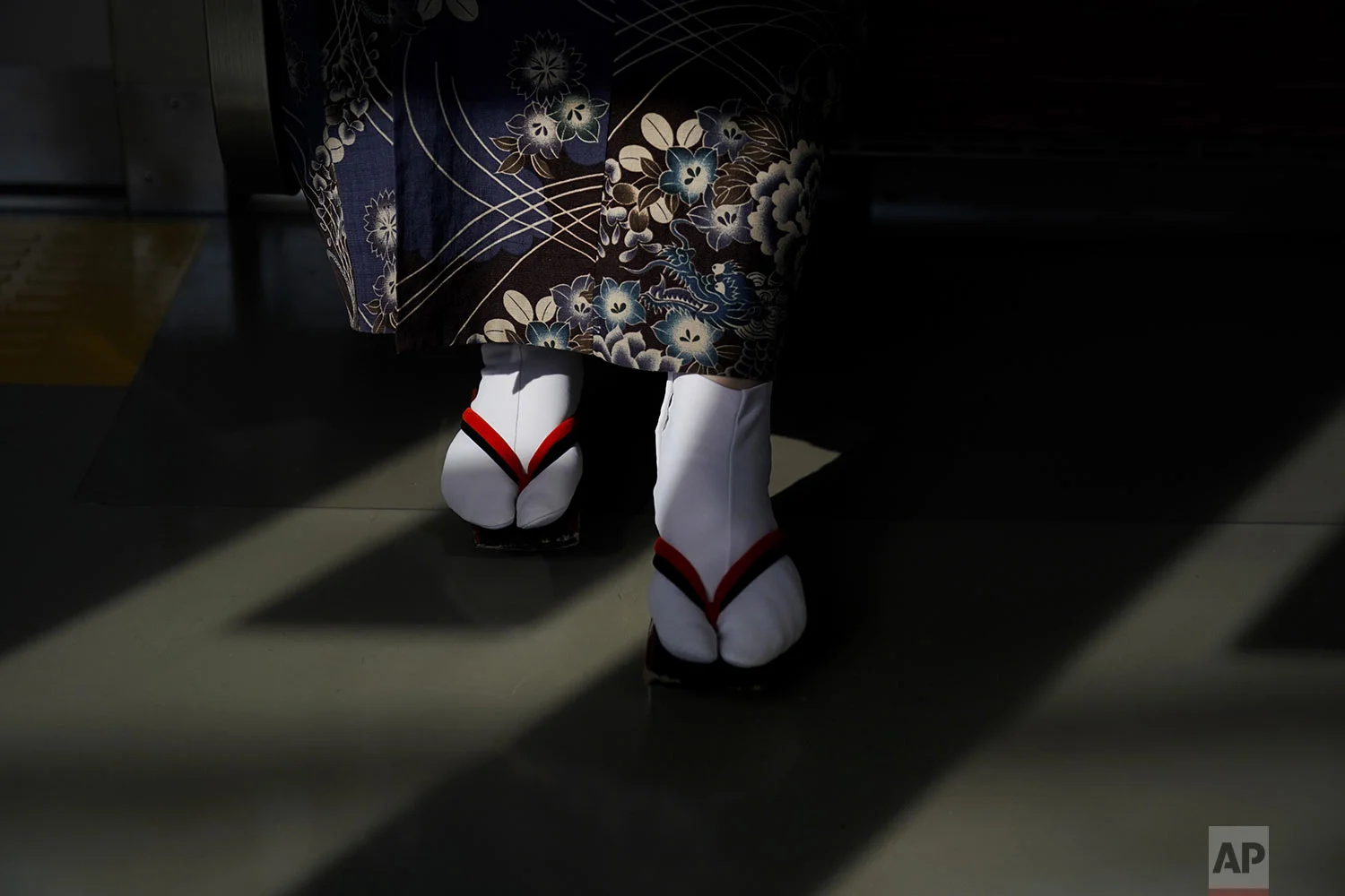 A woman wearing a kimono and traditional Japanese sandals called "geta"" is lit by the afternoon sunlight coming through the window of a train, in Kawagoe, near Tokyo, Friday, Aug. 16, 2019. (AP Photo/Jae C. Hong)