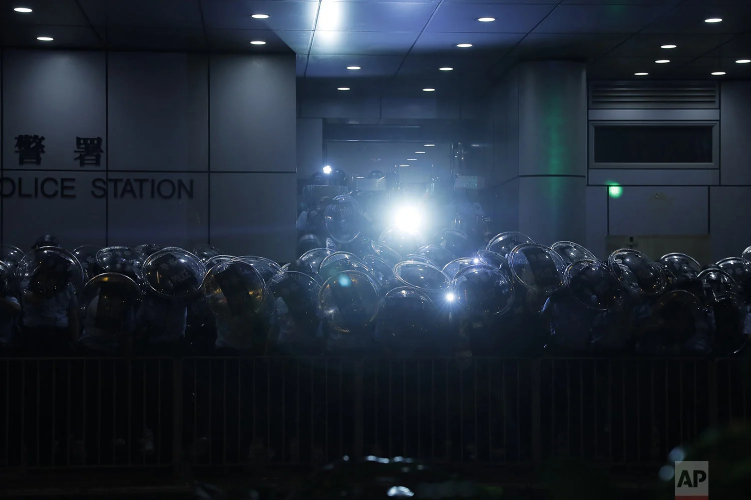 Police officers armed with riot gear stand outside Mong Kok police station during a march by pro-democracy protesters in Hong Kong, Saturday, Aug. 17, 2019. (AP Photo/Kin Cheung)