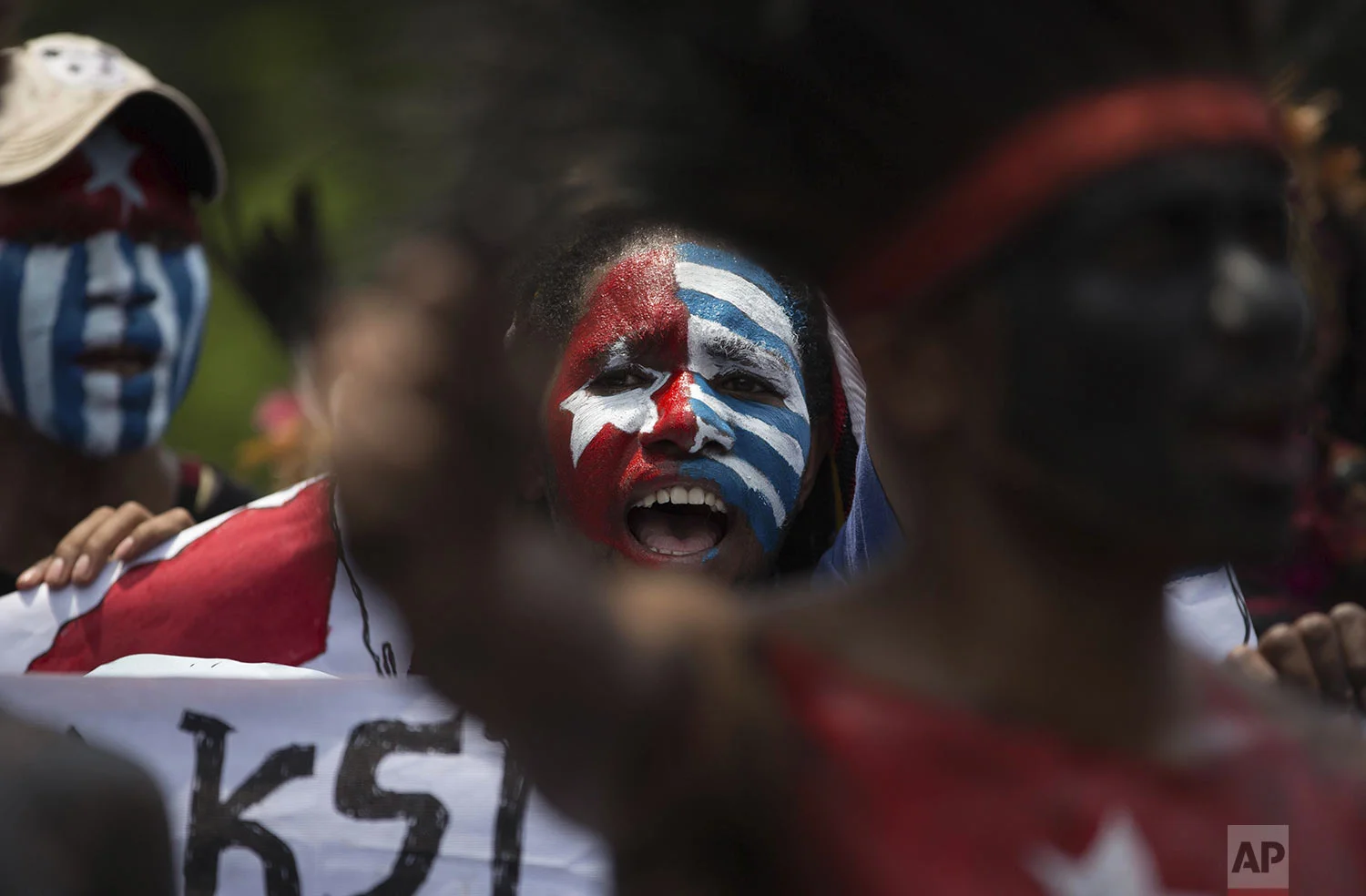 Papuan students, with their body and face painted with the colors of the banned separatist 'Morning Star' flag, shout slogans during a rally in Medan, North Sumatra, Indonesia, Saturday, Aug. 31, 2019. (AP Photo/Binsar Bakkara)