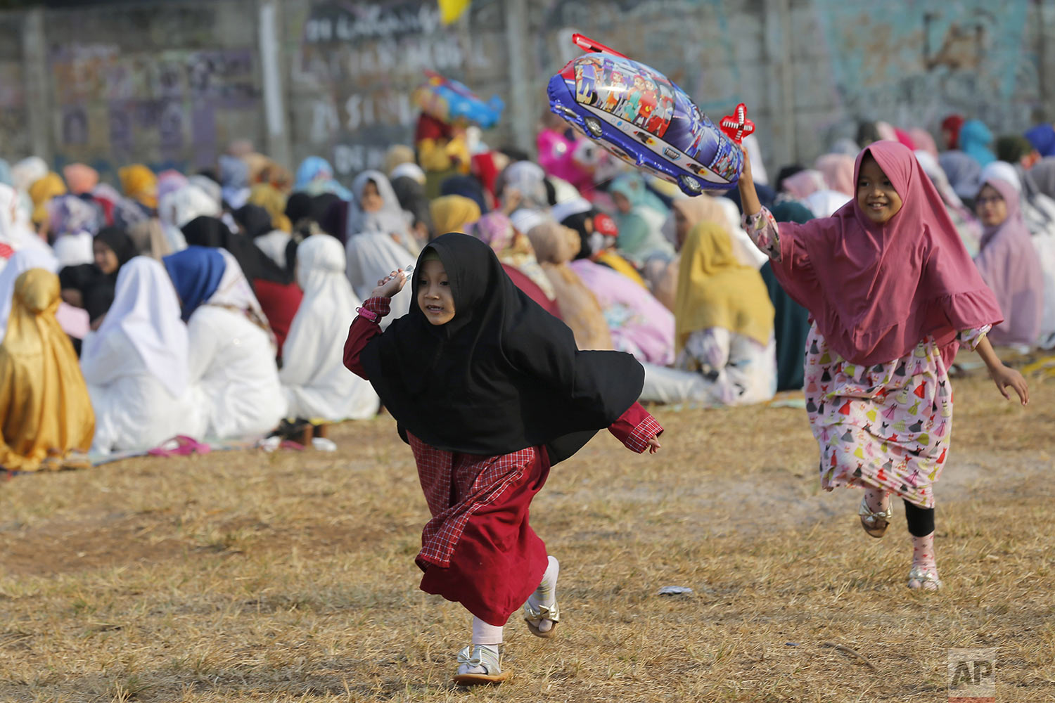  Children play with a balloon after a morning prayer marking Eid al-Adha holidays at a soccer field in South Tangerang, Indonesia, Sunday, Aug. 11, 2019.  (AP Photo/Tatan Syuflana) 