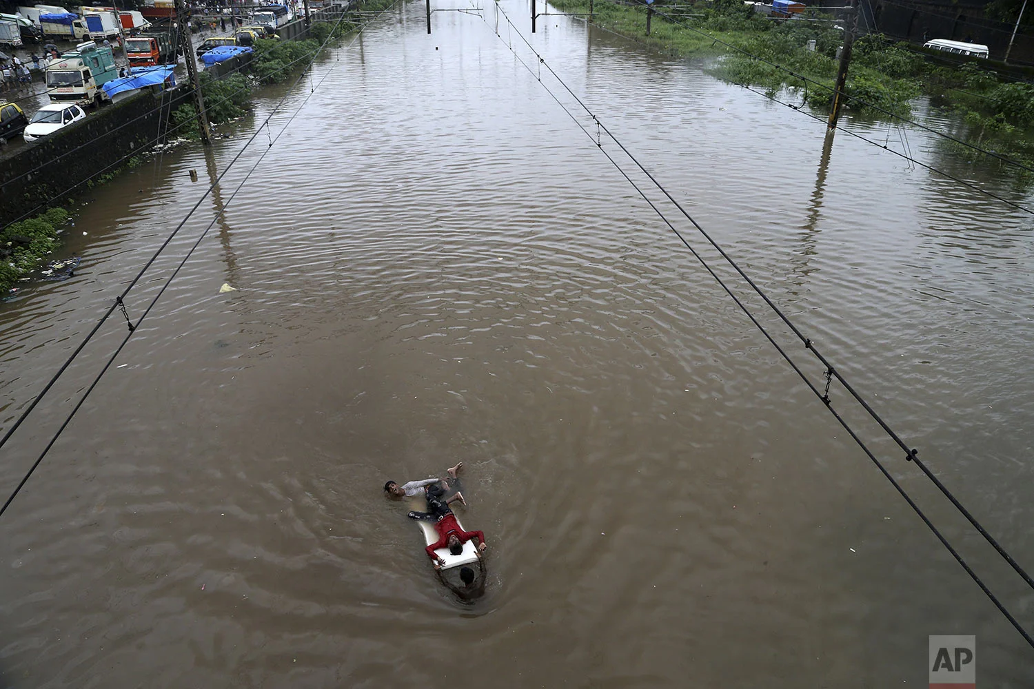 Youth play at a flooded train track following heavy monsoon rains in Mumbai, India, Sunday, Aug. 4, 2019. (AP Photo/Rajanish Kakade)