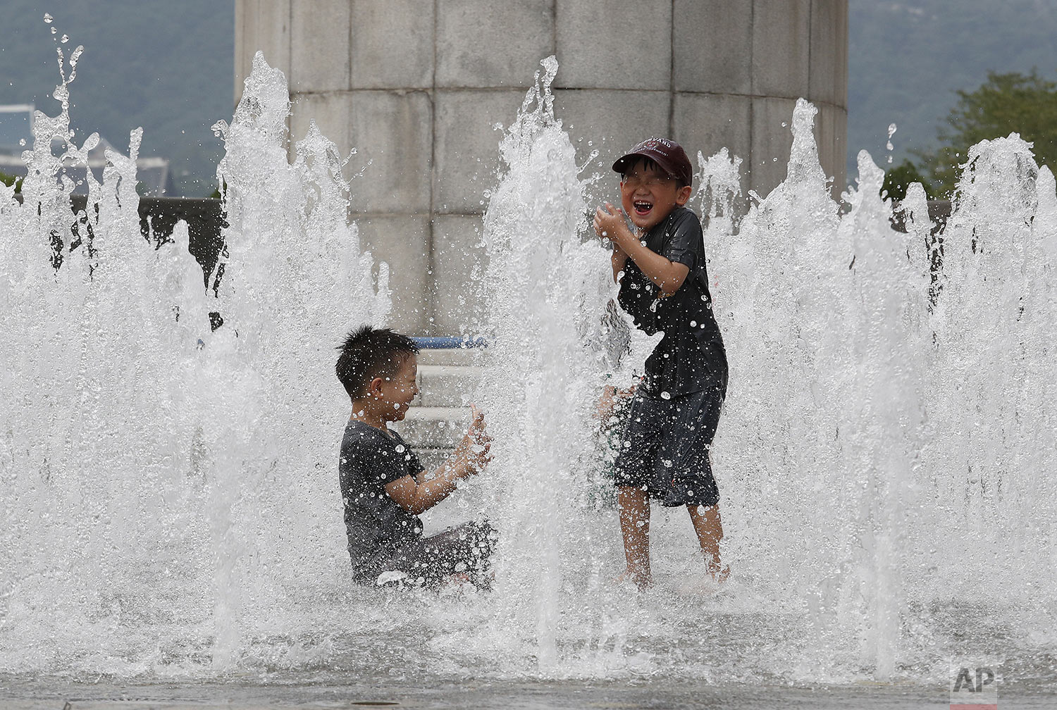  Boys cool off in an outdoor water fountain in Seoul, South Korea, Thursday, Aug. 8, 2019. (AP Photo/Ahn Young-joon) 