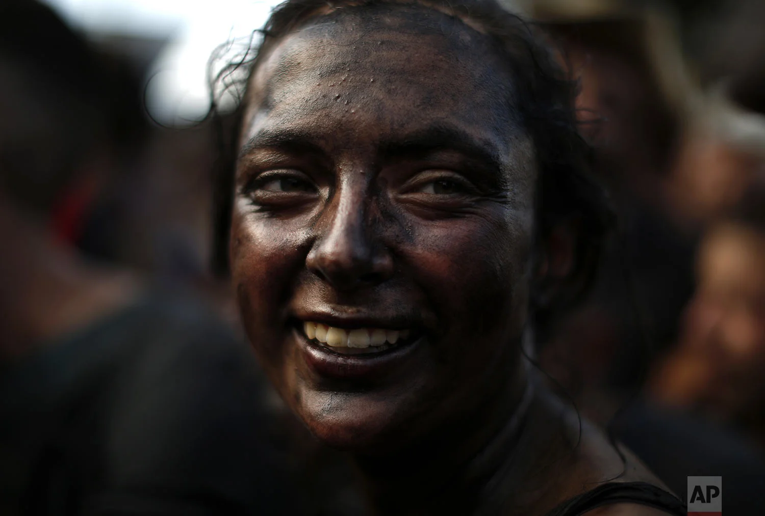 A woman painted with black grease smiles as she takes part at the traditional festivities of the Cascamorras festival in Baza, Spain, Friday, Sept. 6, 2019. (AP Photo/Manu Fernandez)