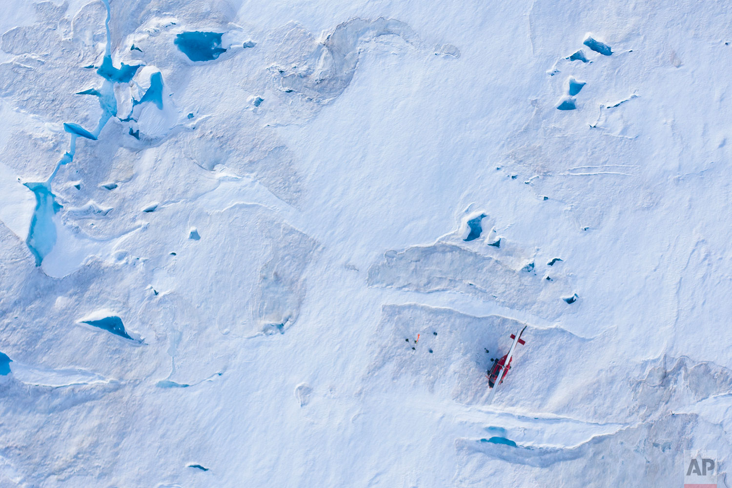 In this Aug. 16, 2019 photo, a helicopter carrying New York University air and ocean scientist David Holland and his team sits on the ice as they install a radar and GPS at the Helheim glacier, in Greenland. (AP Photo/Felipe Dana)