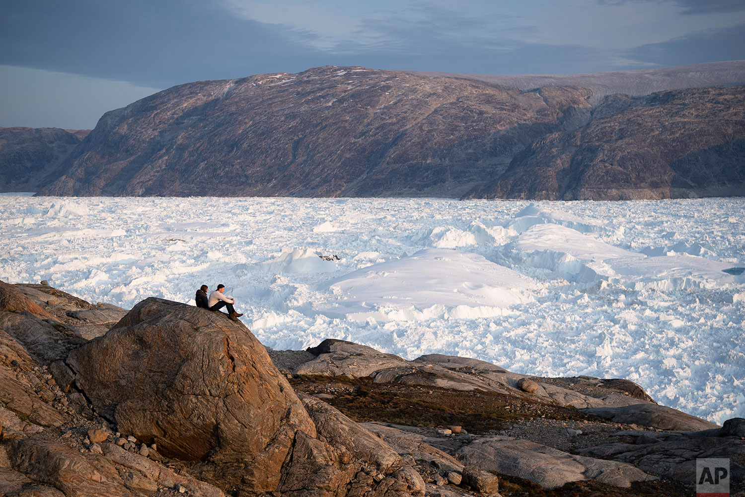 In this Aug. 16, 2019 photo, NYU student researchers sit on top of a rock overlooking the Helheim glacier in Greenland. (AP Photo/Felipe Dana)