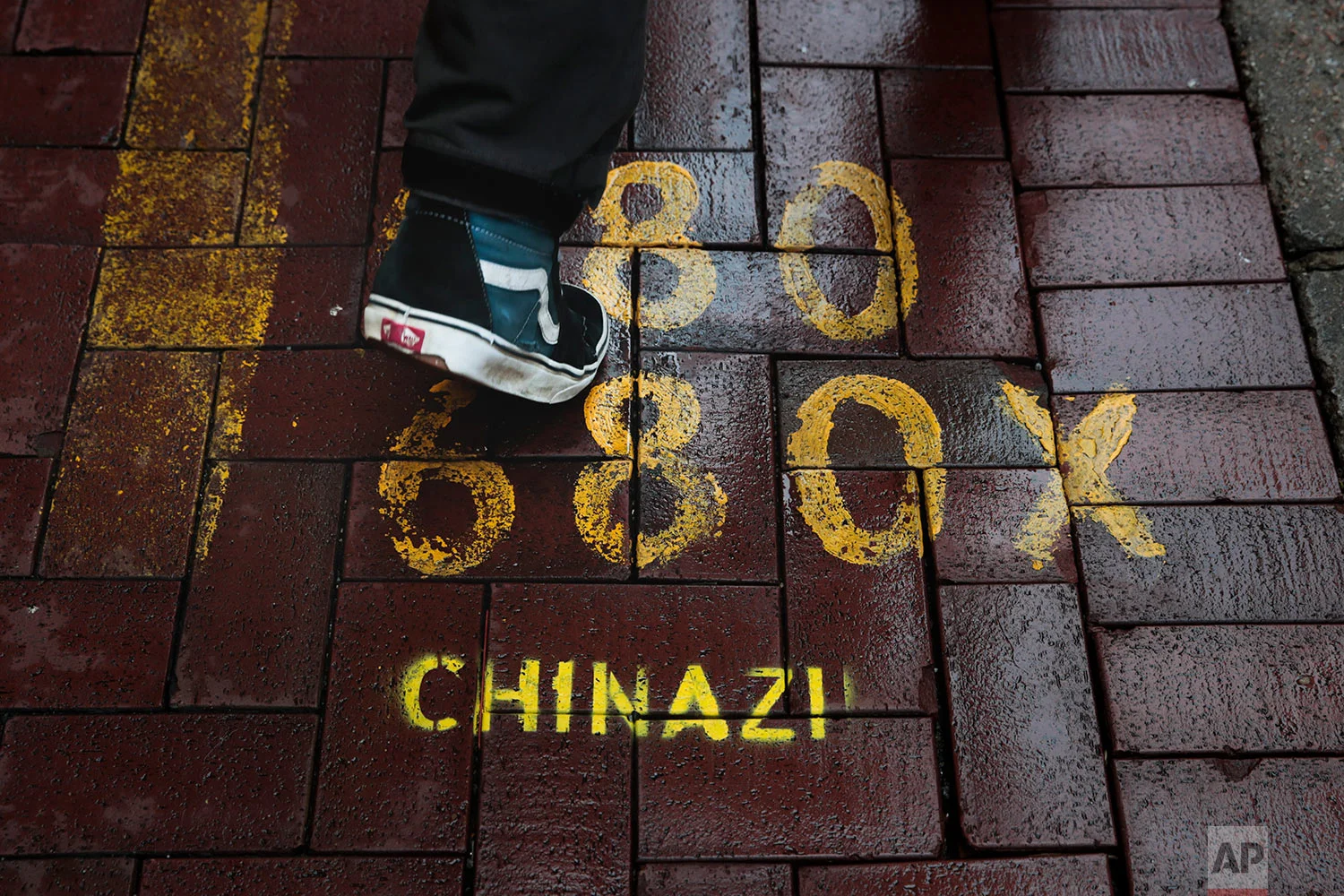 A man walks past a bus stop spray-painted with an anti-China slogan "Chinazi" in Hong Kong, Sept. 4, 2019. (AP Photo/Jae C. Hong)
