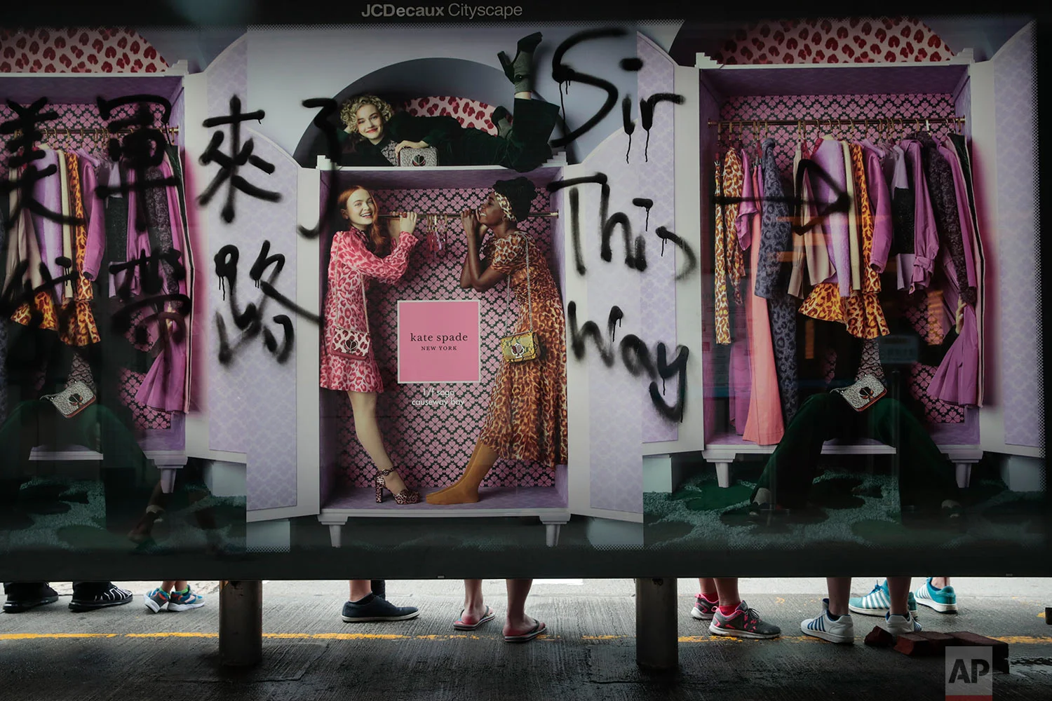 People wait for buses at a bus stop vandalized by protesters in Hong Kong, Sept. 1, 2019. (AP Photo/Jae C. Hong)
