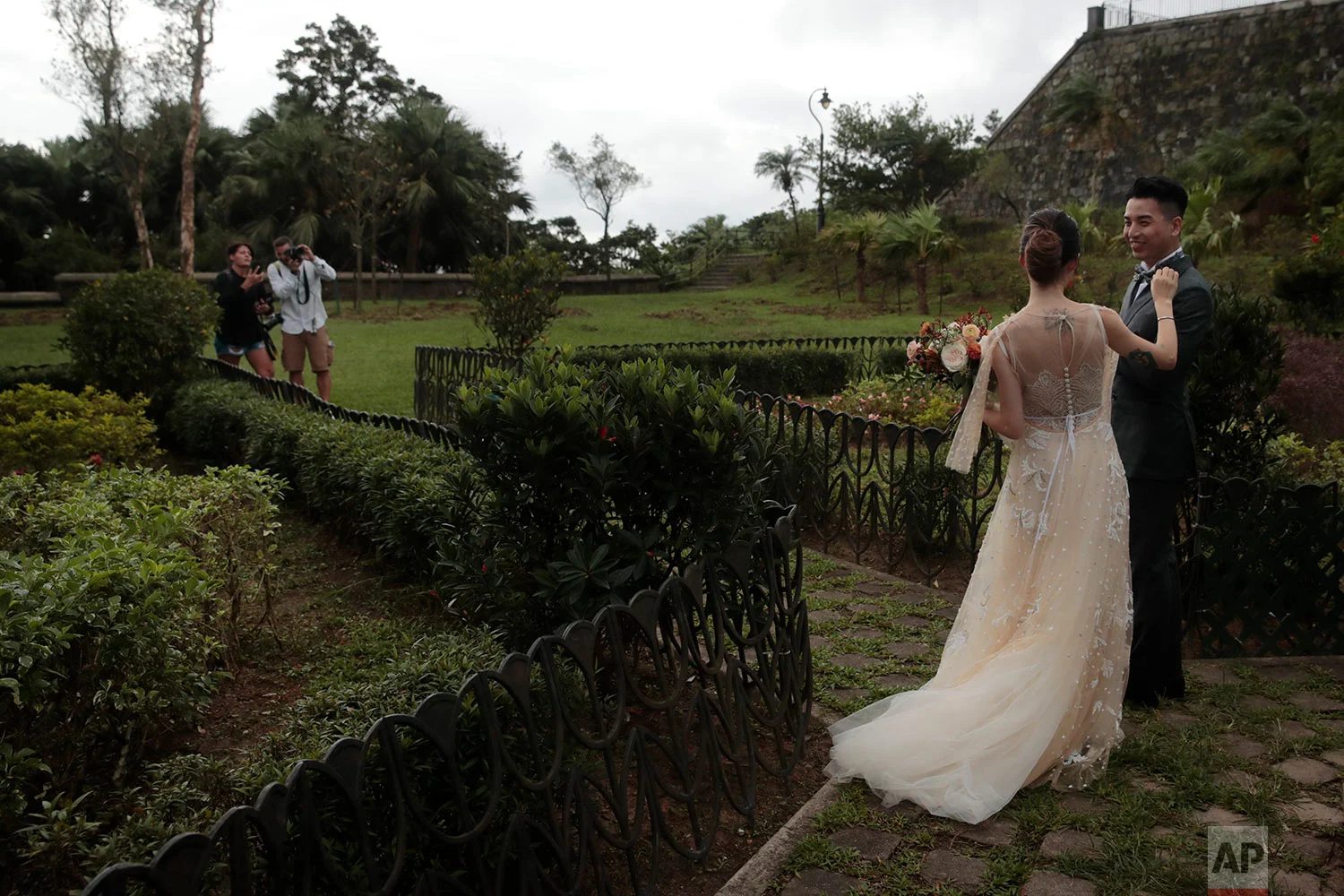 A bride fixes her groom's bow tie during a wedding photoshoot on the top of the Victoria Peak in Hong Kong, Sept. 1, 2019. (AP Photo/Jae C. Hong)