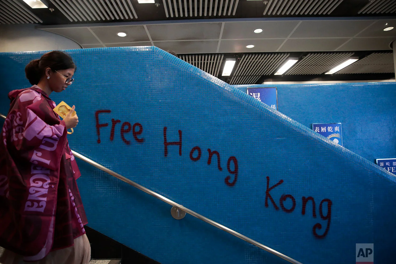 A woman walks past a graffiti at a train station in Hong Kong, Aug. 31, 2019. (AP Photo/Jae C. Hong)