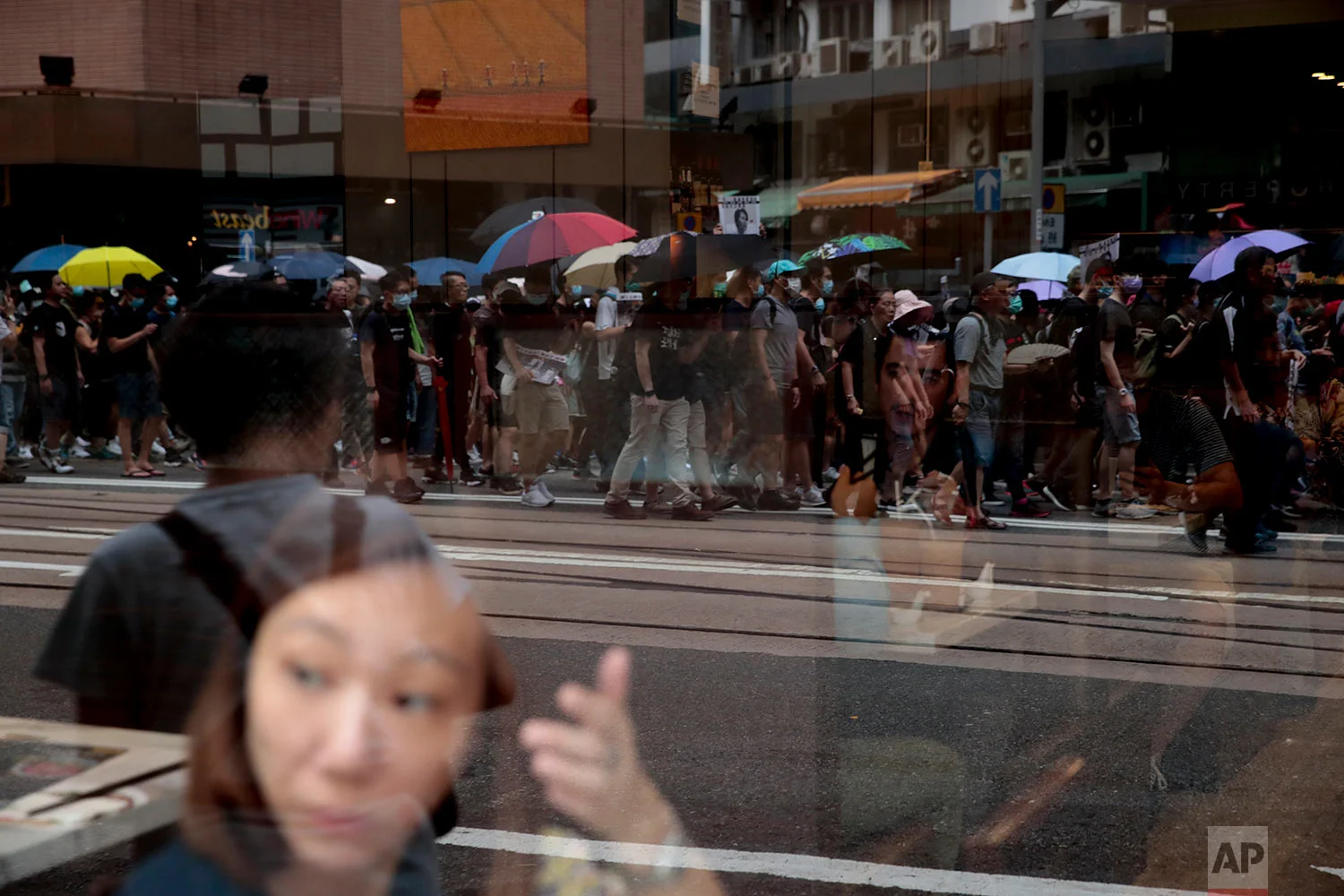 Protesters are reflected on a window as they march during a pro-democracy protest in Wan Chai, Hong Kong, Aug. 31, 2019. (AP Photo/Jae C. Hong)