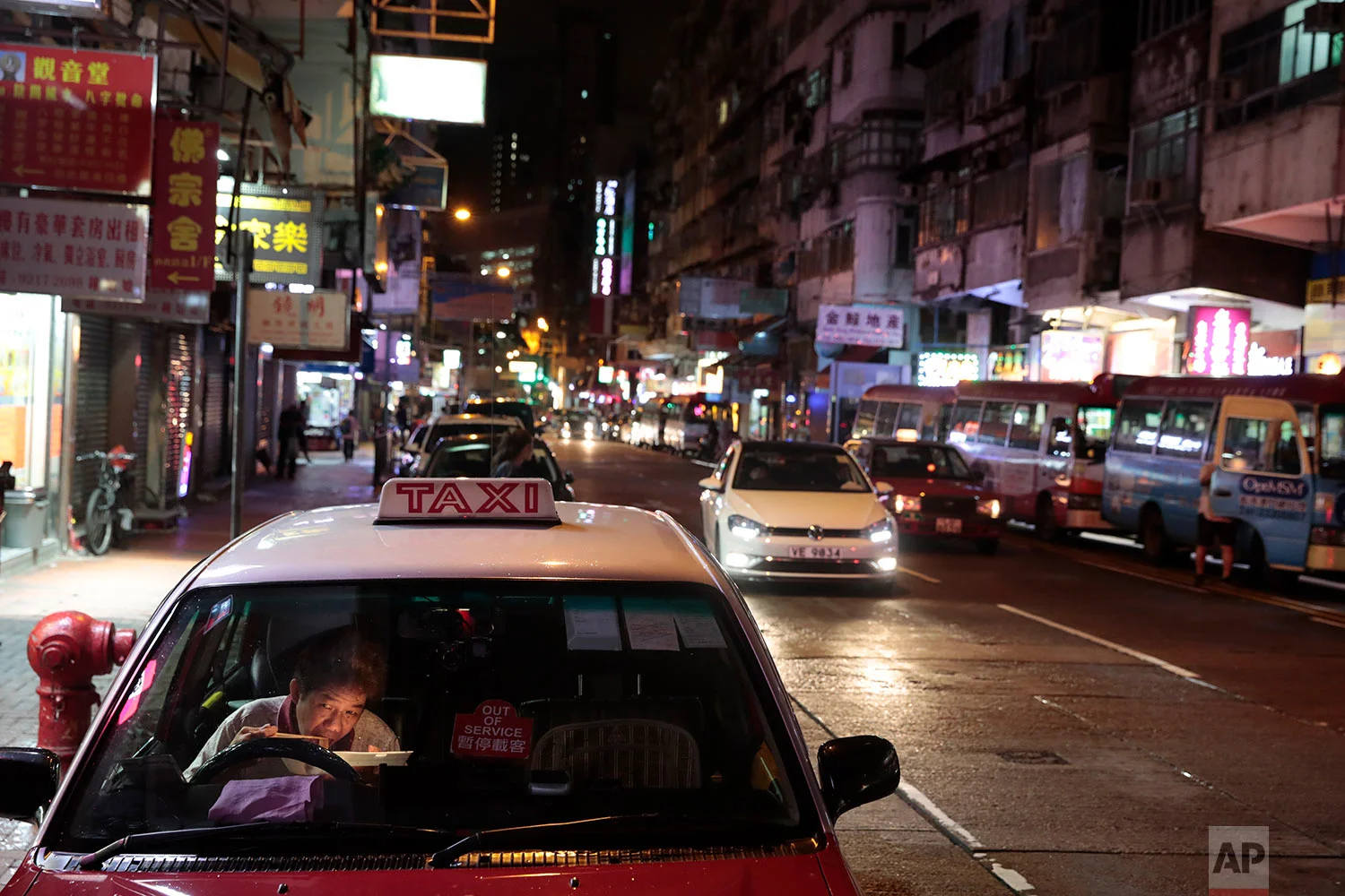 A taxi driver eats his late dinner in his car near the Temple Street Night Market in Hong Kong, Sept. 2, 2019. (AP Photo/Jae C. Hong)