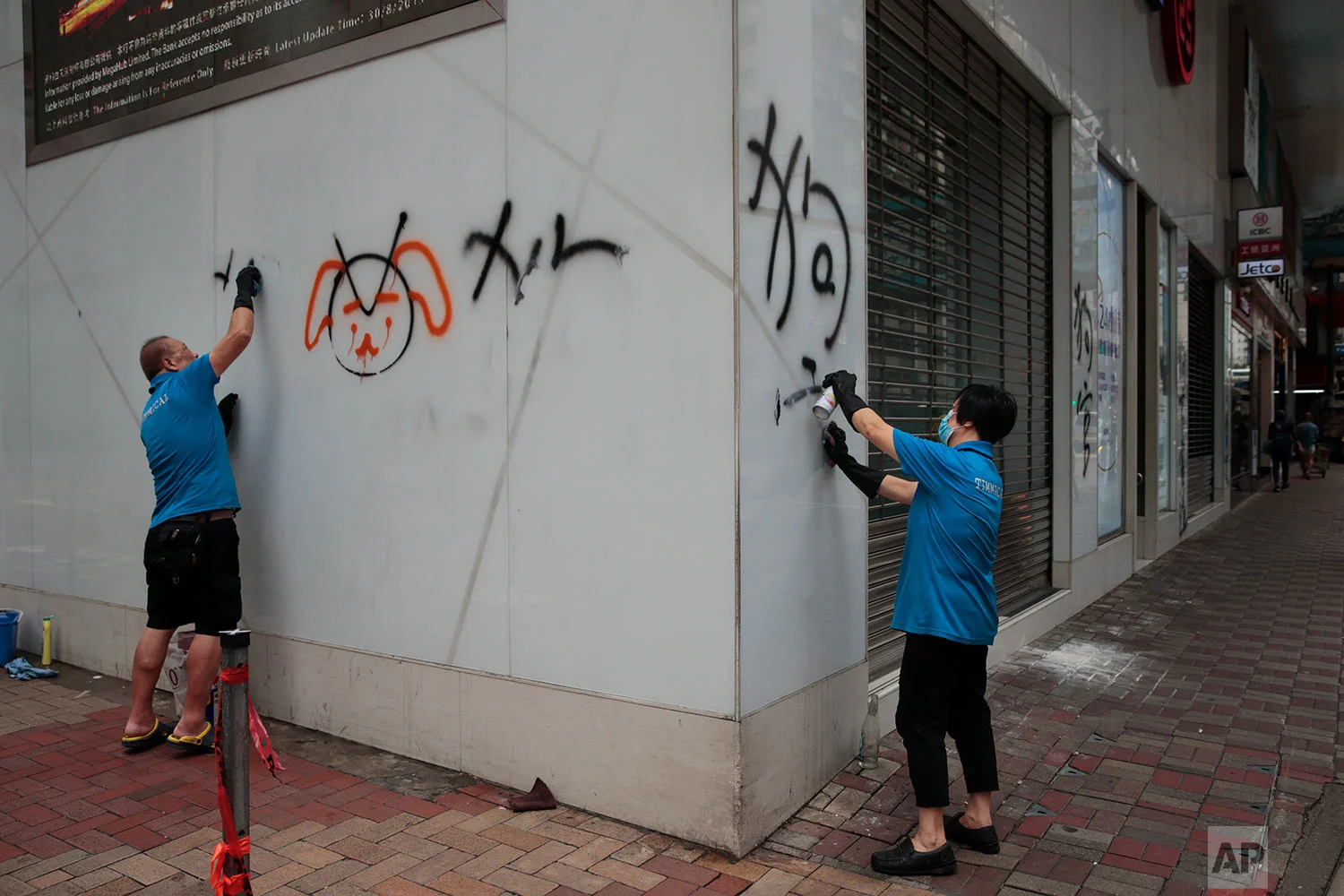 Workers remove graffiti left by protesters during a protest the night before in Hong Kong, Sept. 1, 2019. (AP Photo/Jae C. Hong)