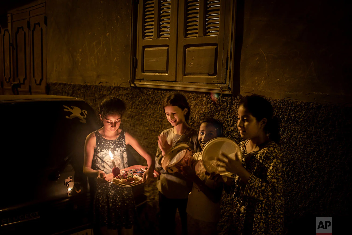 Girls carry a tray and play with drums outside their home to collect treats and dry fruits, in celebration of Ashura, in Sale, near Rabat, Morocco, Sept. 9, 2019. (AP Photo/Mosa'ab Elshamy)