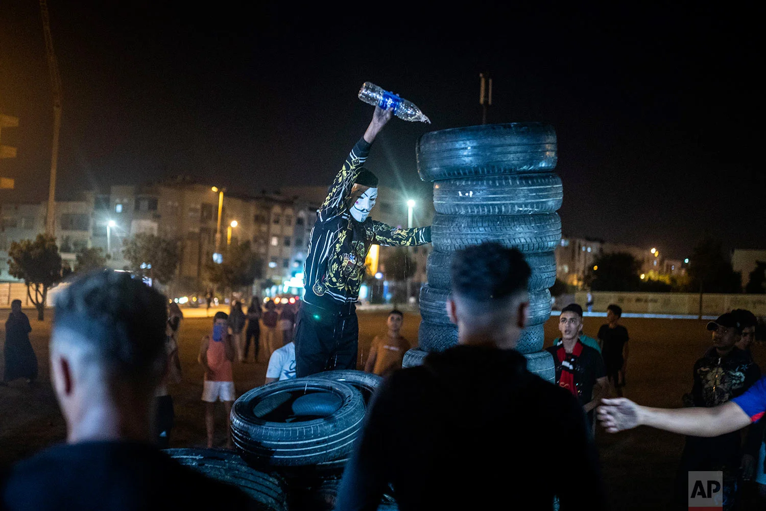 A youth pours kerosene over tires to light a bonfire in celebration of Ashura, in Sale, near Rabat, Morocco, Sept. 9, 2019. (AP Photo/Mosa'ab Elshamy)