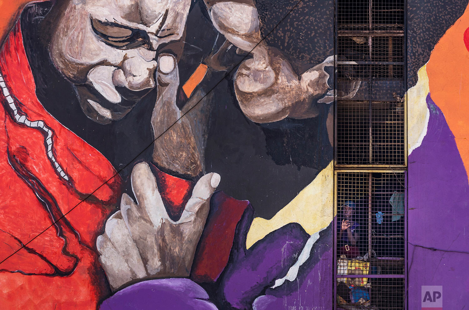 A resident looks out from the stairwell of her housing block, on which is painted an informational mural against sexual abuse, in the low income neighborhood of Mbare, known to have many supporters of former president Robert Mugabe's ZANU-PF party, in the capital Harare, Zimbabwe, Sept. 9, 2019. (AP Photo/Ben Curtis)