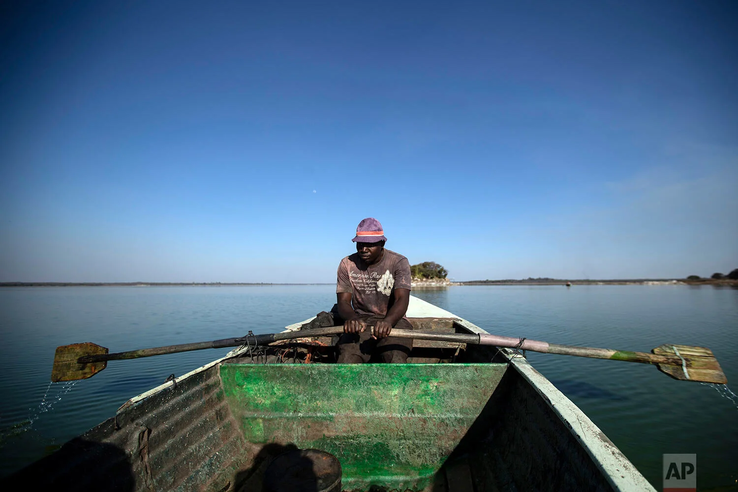 A fisherman rows his boat after casting his nets for the night, in Lake Chivero, west of the capital Harare, in Zimbabwe, Sept. 10, 2019. (AP Photo/Ben Curtis)