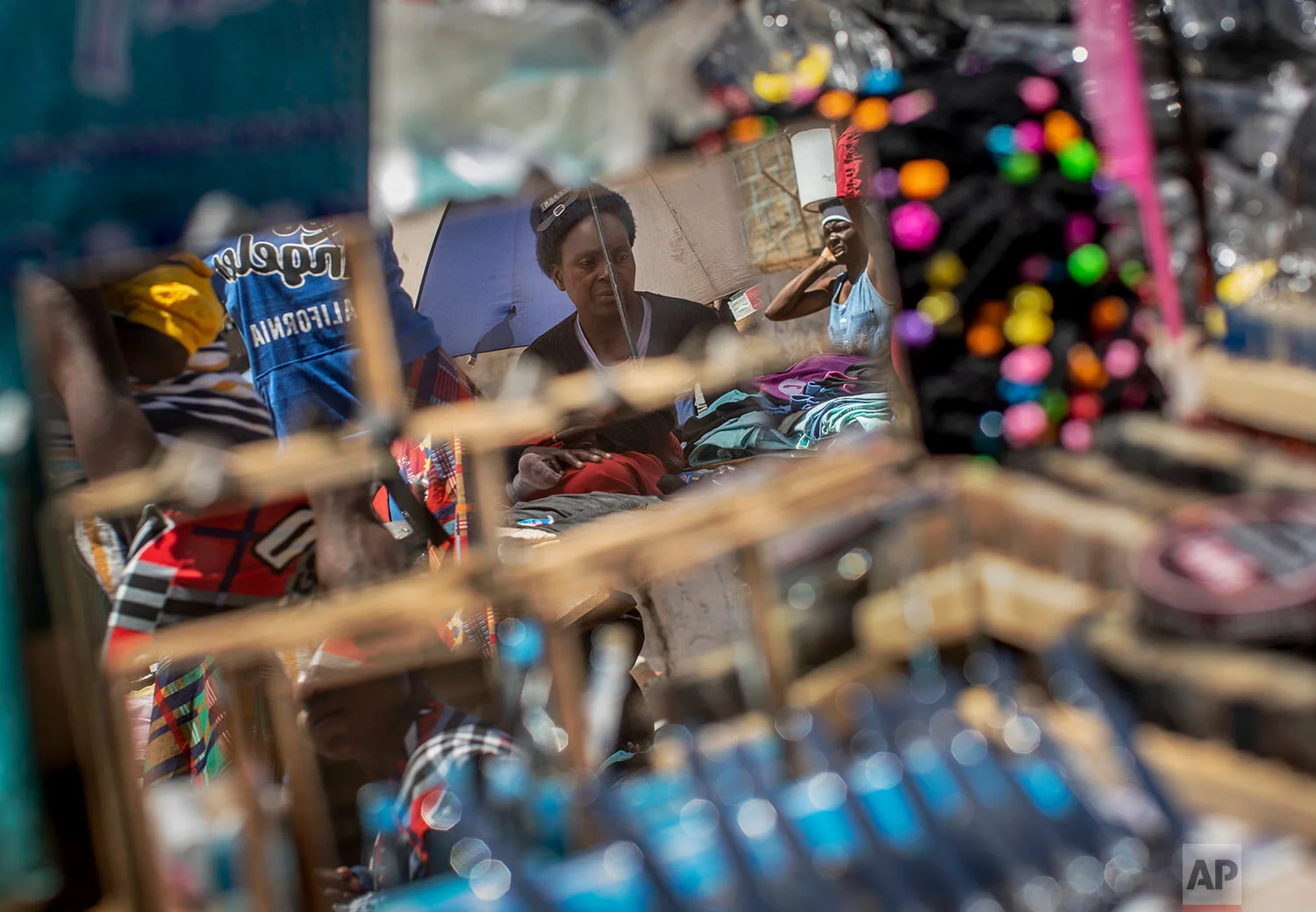 A street seller is seen reflected in mirrors for sale, at a market in the low income neighborhood of Mbare, known to have many supporters of former president Robert Mugabe's ZANU-PF party, in the capital Harare, Zimbabwe, Sept. 9, 2019. (AP Photo/Ben Curtis)