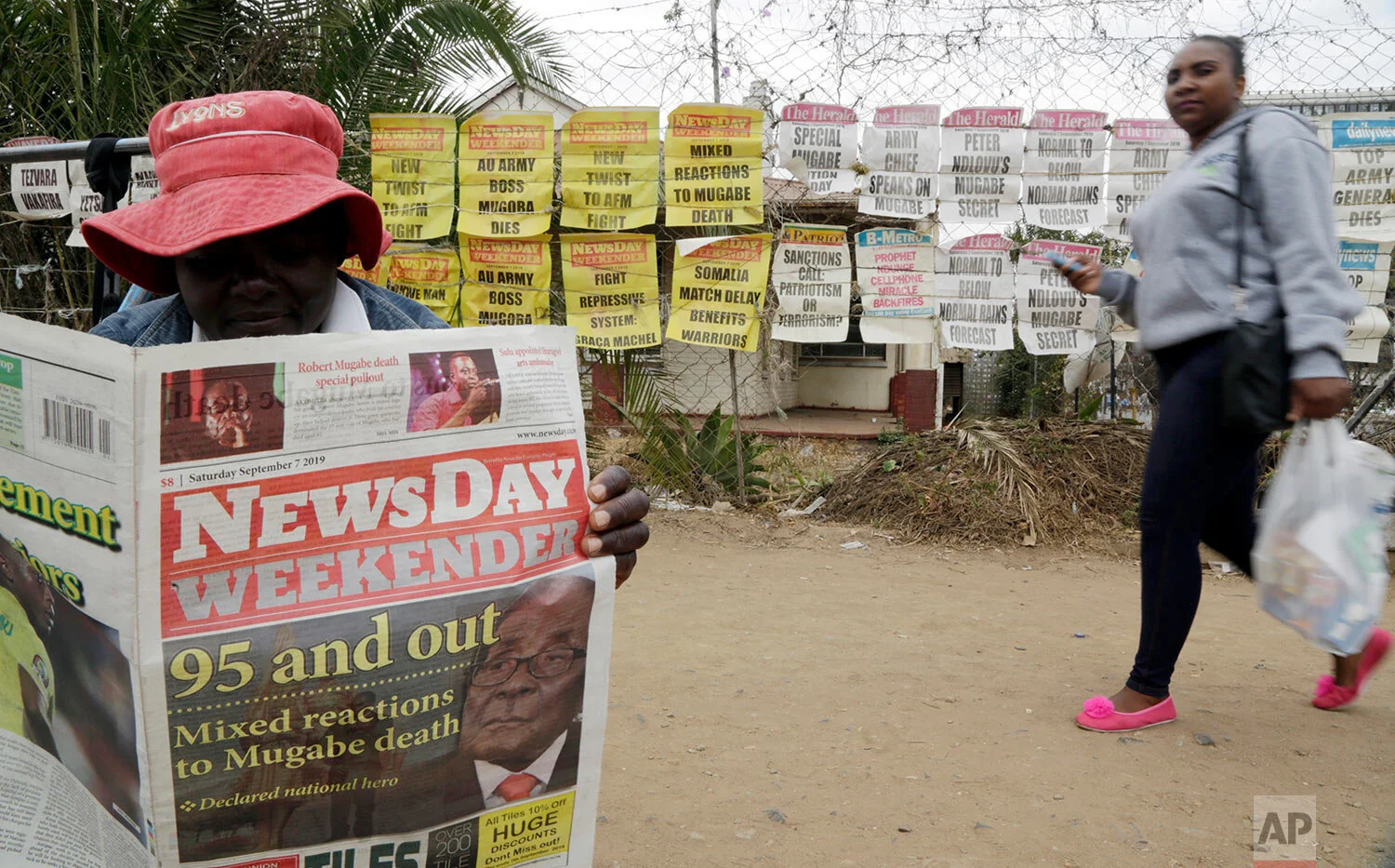 An ice cream vendor reads a newspaper on a street in Harare, Zimbabwe, Sept. 7, 2019. (AP Photo/Themba Hadebe)
