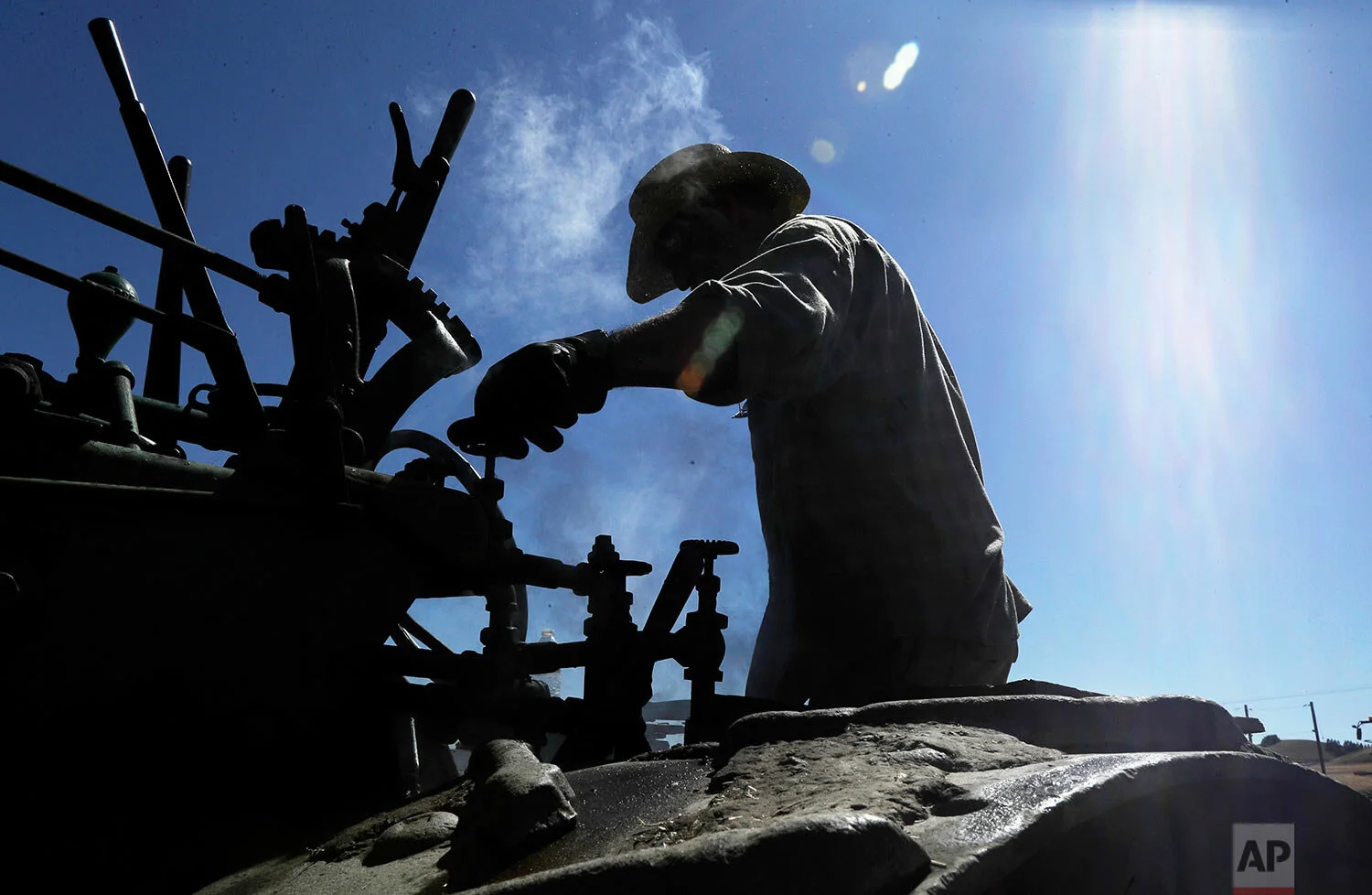 Charles Knaack operates a 100-year-old Case steam traction engine being used to drive a stationary grain thresher near Colfax, Wash., Sept. 2, 2019. (AP Photo/Ted S. Warren)