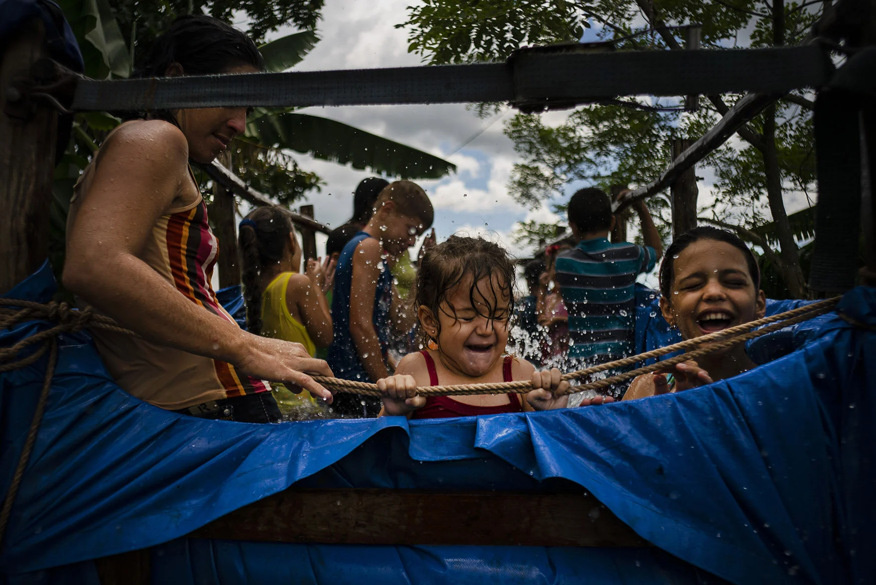 A girl holds on to the ropes of a swimming pool created in the bed of a tractor trailer in El Infernal neighborhood of San Andres, in Cuba's province Pinar del Río, on Saturday, Aug. 24, 2019. In a neighborhood far from recreation centers, community members helped to make the idea of the tractor pool a reality, lending tarps, providing water and paying for the tractor's gasoline. (AP Photo/Ramon Espinosa)