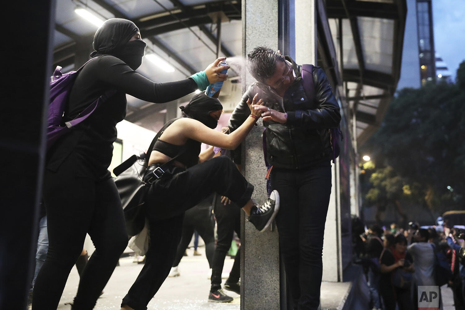  Two women attack a male commuter, one spraying him in the face with paint another kicking him, at a bus station, during a protest sparked by a string of alleged sexual attacks by police officers, in Mexico City, Aug. 16, 2019. On Friday, hundreds of