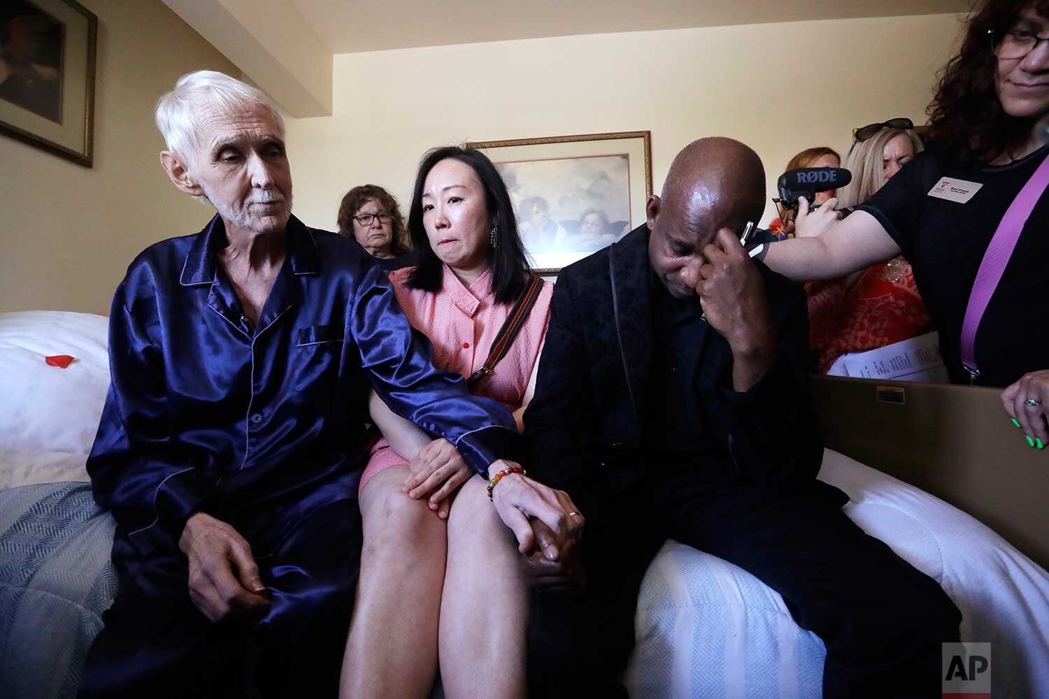  In this May 10, 2019, photo, Robert Fuller, left, consoles friends gathered on and near his bed as he makes his final preparations before dying, in Seattle. (AP Photo/Elaine Thompson) 