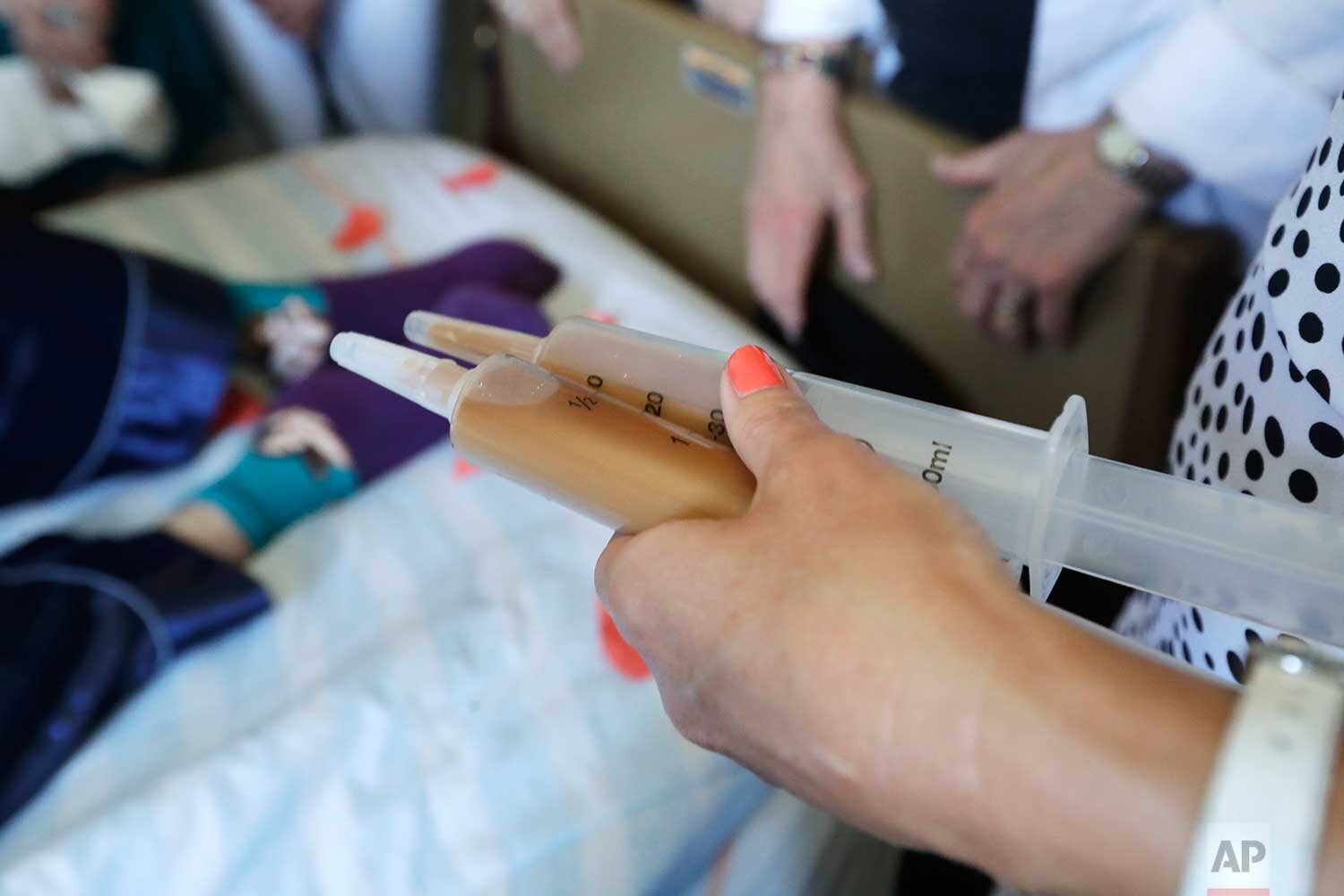 In this May 10, 2019, photo, End of Life Washington volunteer Stephanie Murray brings the drugs that will end the life of Robert Fuller to him as he lies in bed, in Seattle. (AP Photo/Elaine Thompson)