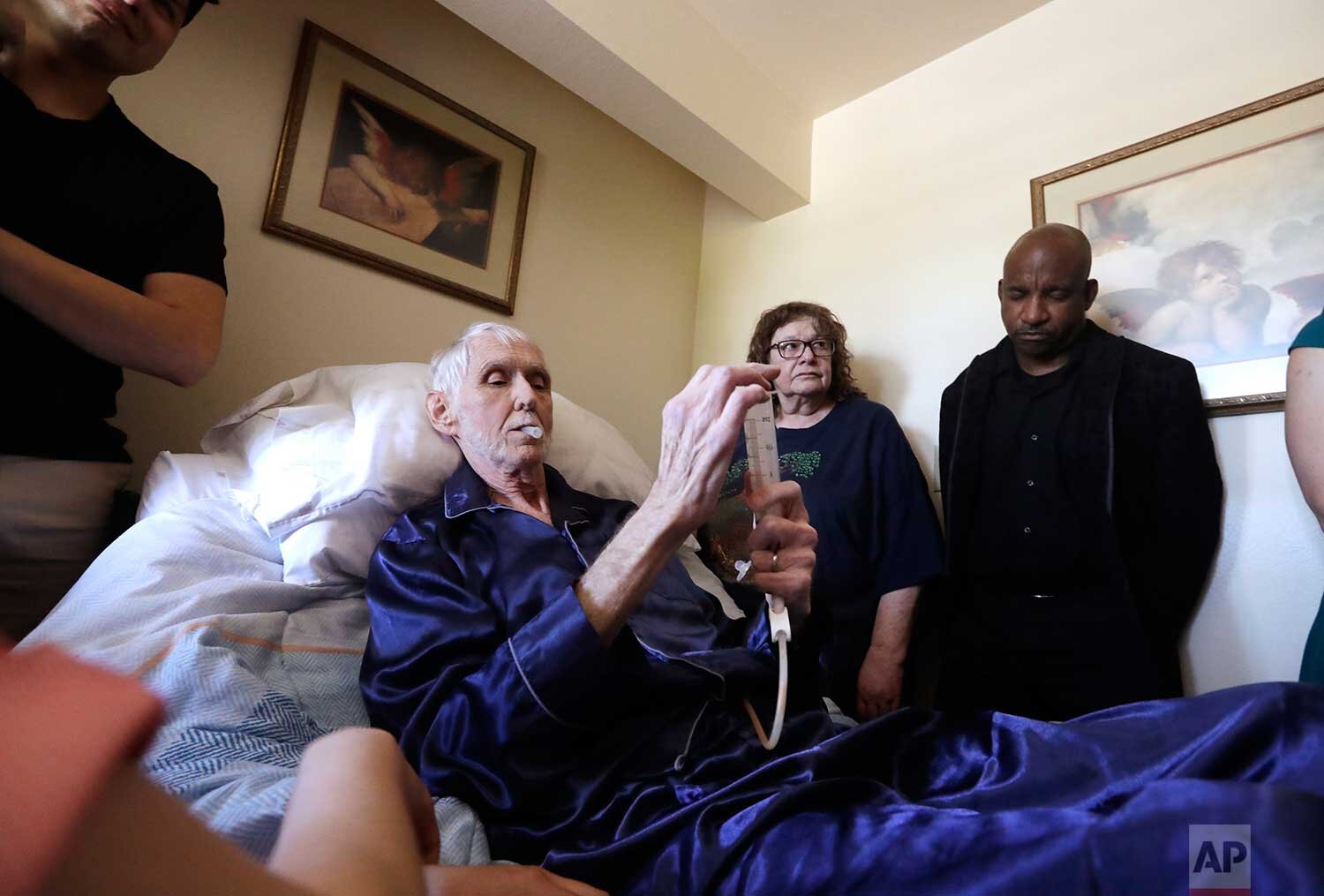 In this May 10, 2019, photo, Robert Fuller begins to plunge the drugs that will end his life into his feeding tube in Seattle. (AP Photo/Elaine Thompson)