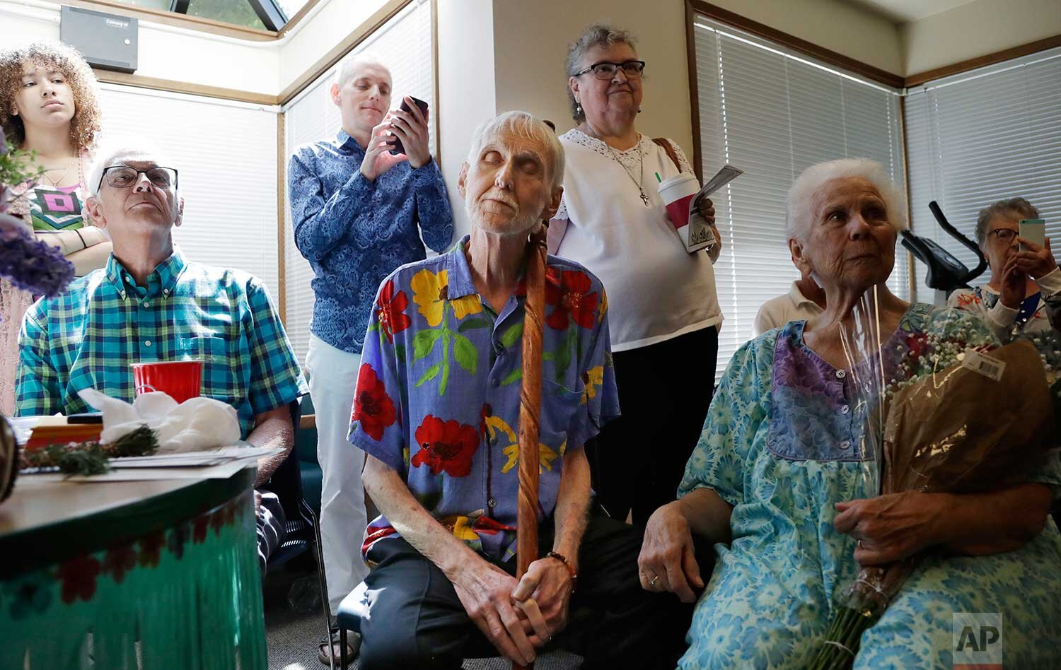  In this May 10, 2019, photo, Robert Fuller, center, leans on his walking stick and closes his eyes as he listens to music at a party in his honor in Seattle. (AP Photo/Elaine Thompson) 