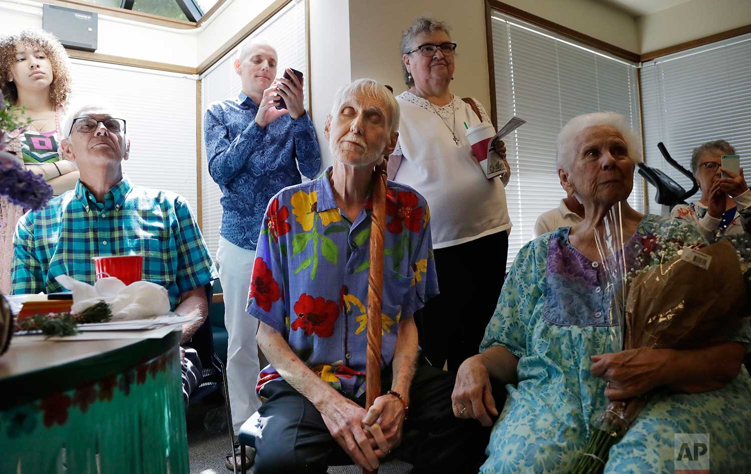 In this May 10, 2019, photo, Robert Fuller, center, leans on his walking stick and closes his eyes as he listens to music at a party in his honor in Seattle. (AP Photo/Elaine Thompson)