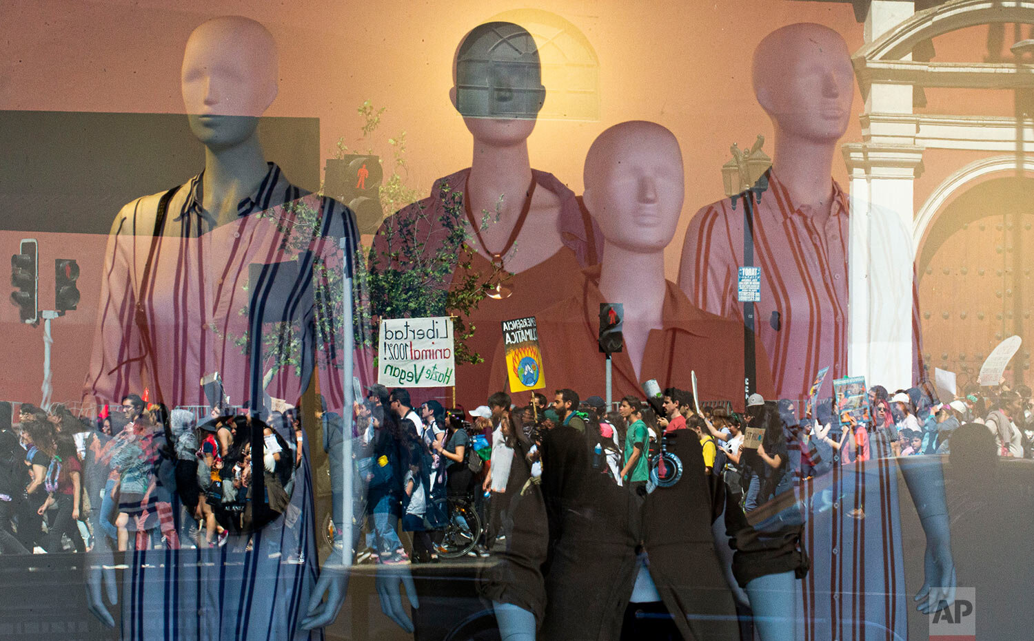  Demonstrators taking part in a global protest on climate change are reflected in a clothing store window, in Santiago, Chile, Friday, Sept. 20, 2019. Across the globe, hundreds of thousands took to the streets to demand that leaders tackle climate c