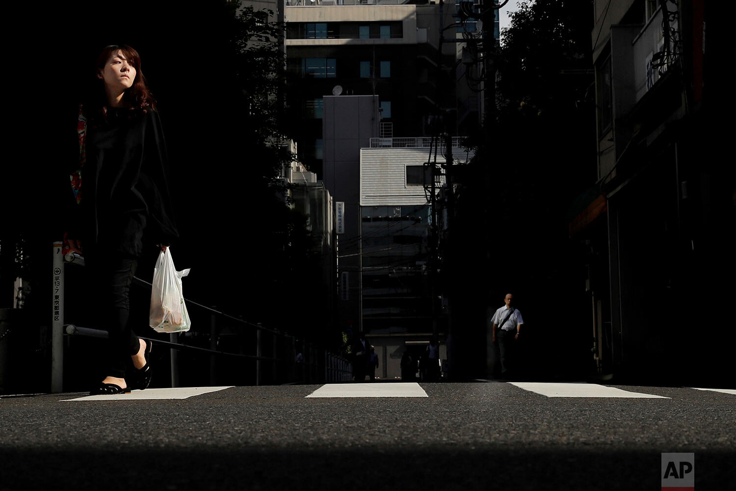  A woman crosses the street in the Shinbashi district of Tokyo, Japan, Friday, Sept. 20, 2019. (AP Photo/Christophe Ena) 