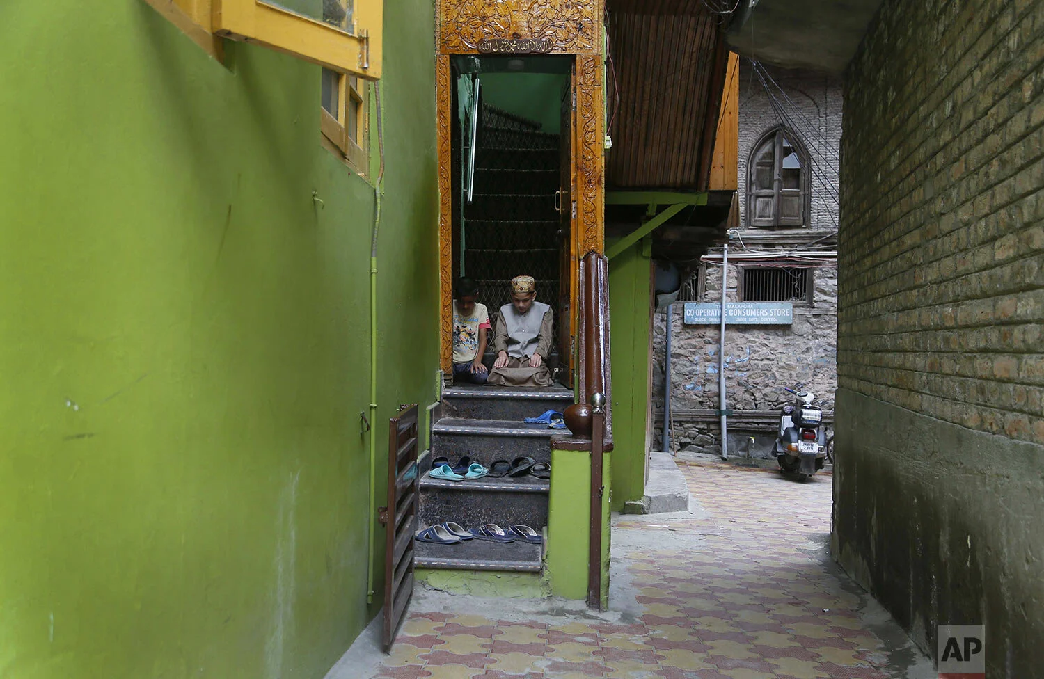 Muslim boys offer Friday prayers at the doorway of a local mosque in an alley during curfew-like restrictions in Srinagar, Friday, Aug. 16, 2019. (AP Photo/Mukhtar Khan)