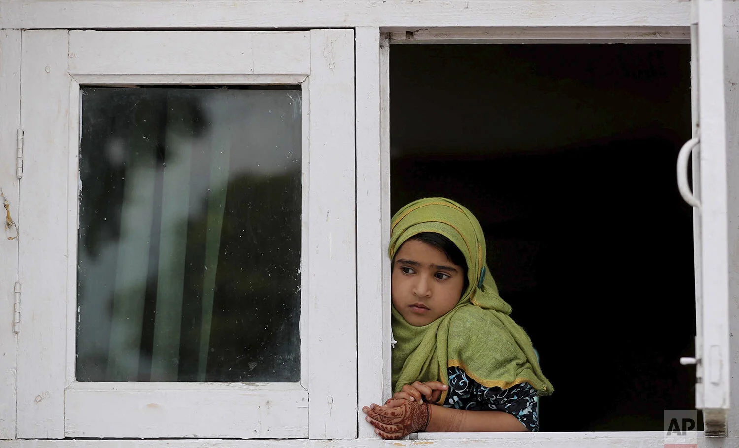 A child watches a protest from the window of a shrine in Srinagar, Indian controlled Kashmir, Friday, Aug. 30, 2019. (AP Photo/Mukhtar Khan)