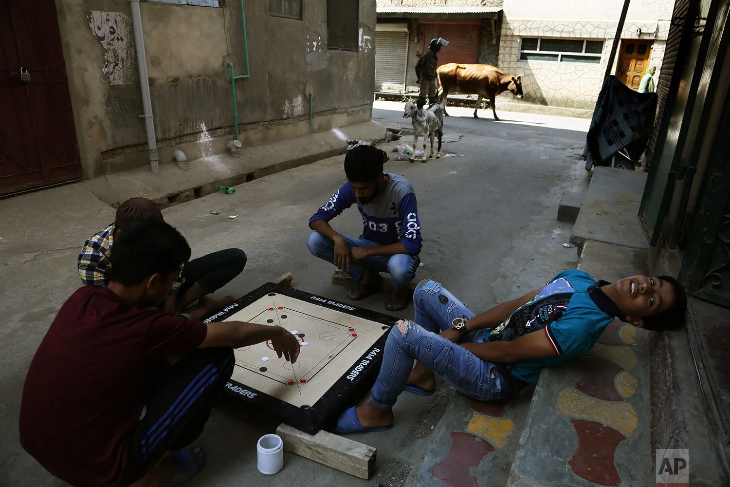 Children play carrom board as an Indian paramilitary soldier stands guard at a closed market area in Srinagar, Indian controlled Kashmir, Tuesday, Sept. 17, 2019. (AP Photo/Mukhtar Khan)