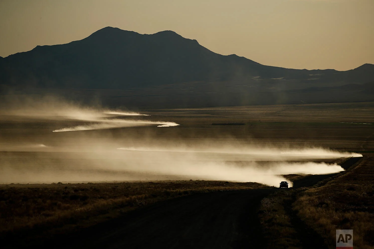 Cars kick up dust as they drive along a road that leads to an entrance to the Nevada Test and Training Range near Area 51, Friday, Sept. 20, 2019, near Rachel, Nev. (AP Photo/John Locher)