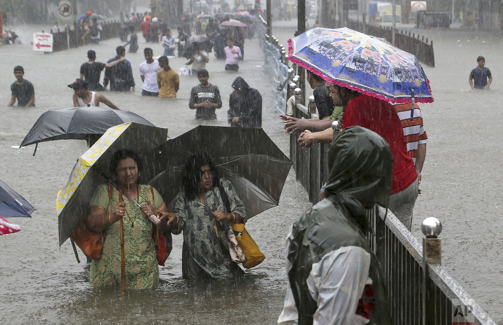 People navigate their way through a flooded street as it rains in Mumbai, India, Wednesday, Sept. 4, 2019. (AP Photo/Rajanish Kakade)
