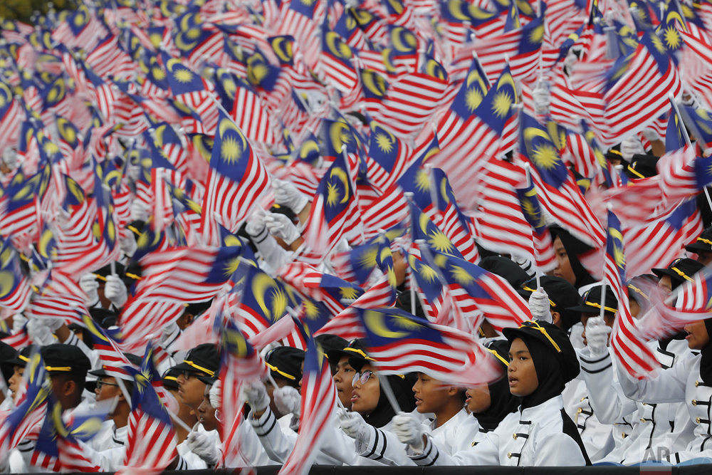Students wave national flags during 62nd Independence Day celebrations in Putrajaya, Malaysia, Saturday, Aug. 31, 2019. (AP Photo/Vincent Thian)