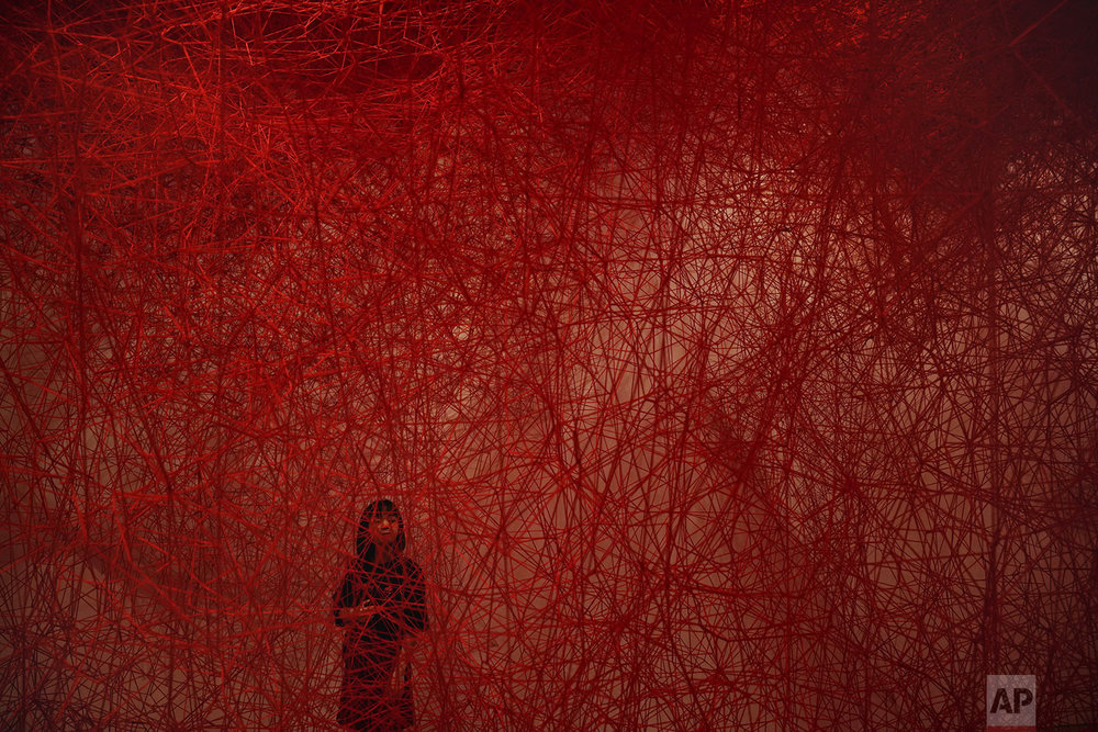 A woman looks at Chiharu Shiota's art installation titled "Uncertain Journey" at the Mori Art Museum, in Tokyo, Thursday, Sept. 19, 2019. (AP Photo/Jae C. Hong)
