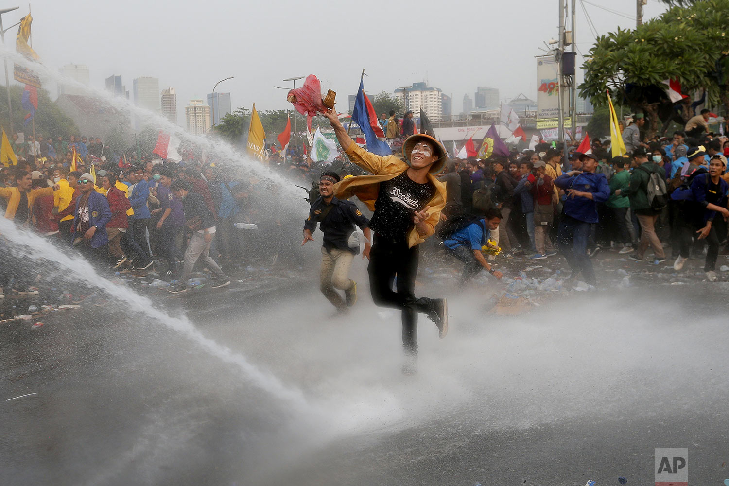  Student protesters hurl objects as they are sprayed by a police water cannon truck during a protest outside the parliament in Jakarta, Indonesia, Tuesday, Sept. 24, 2019.  (AP Photo/Tatan Syuflana) 