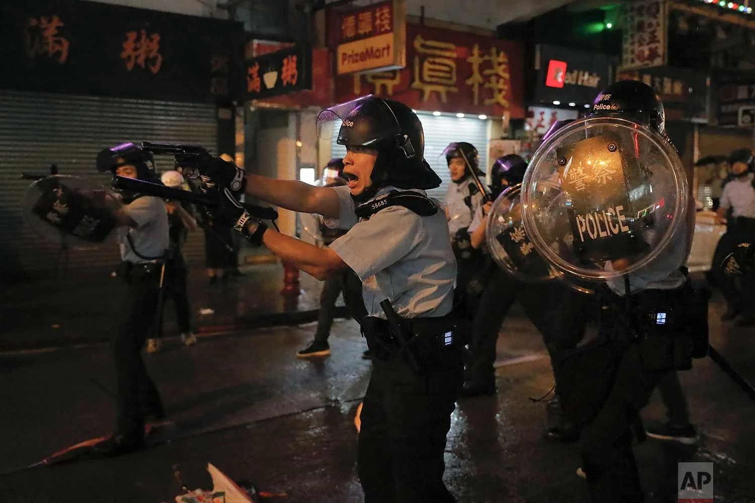 Policemen pull out their guns after a confrontation with demonstrators during a protest in Hong Kong, Sunday, Aug. 25, 2019. Hong Kong police have rolled out water cannon trucks for the first time in this summer's pro-democracy protests. The two trucks moved forward with riot officers Sunday evening as they pushed protesters back along a street in the outlying Tsuen Wan district. (AP Photo/Vincent Yu)