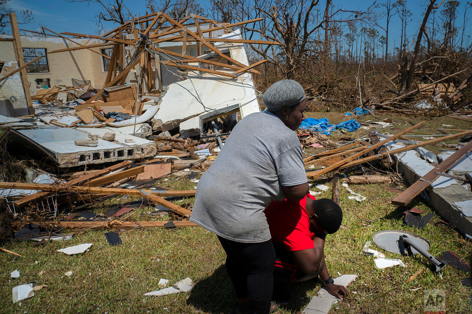 A woman comforts a man who cries after discovering his shattered house and not knowing anything about his 8 relatives who lived in the house, missing in the aftermath of Hurricane Dorian, in High Rock, Grand Bahama, Bahamas, Thursday, Sept. 5, 2019. (AP Photo/Ramon Espinosa)