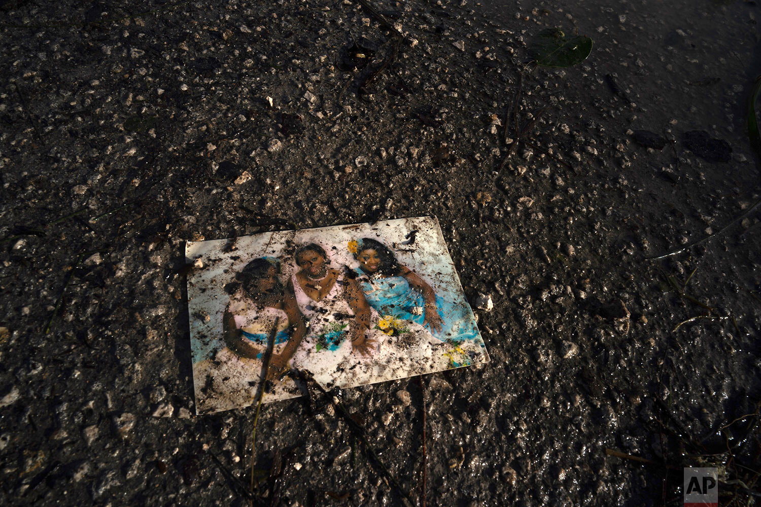 A family photo lies on a muddied road in the aftermath of Hurricane Dorian in Pine Bay, near Freeport, Bahamas, Wednesday, Sept. 4, 2019. (AP Photo/Ramon Espinosa)